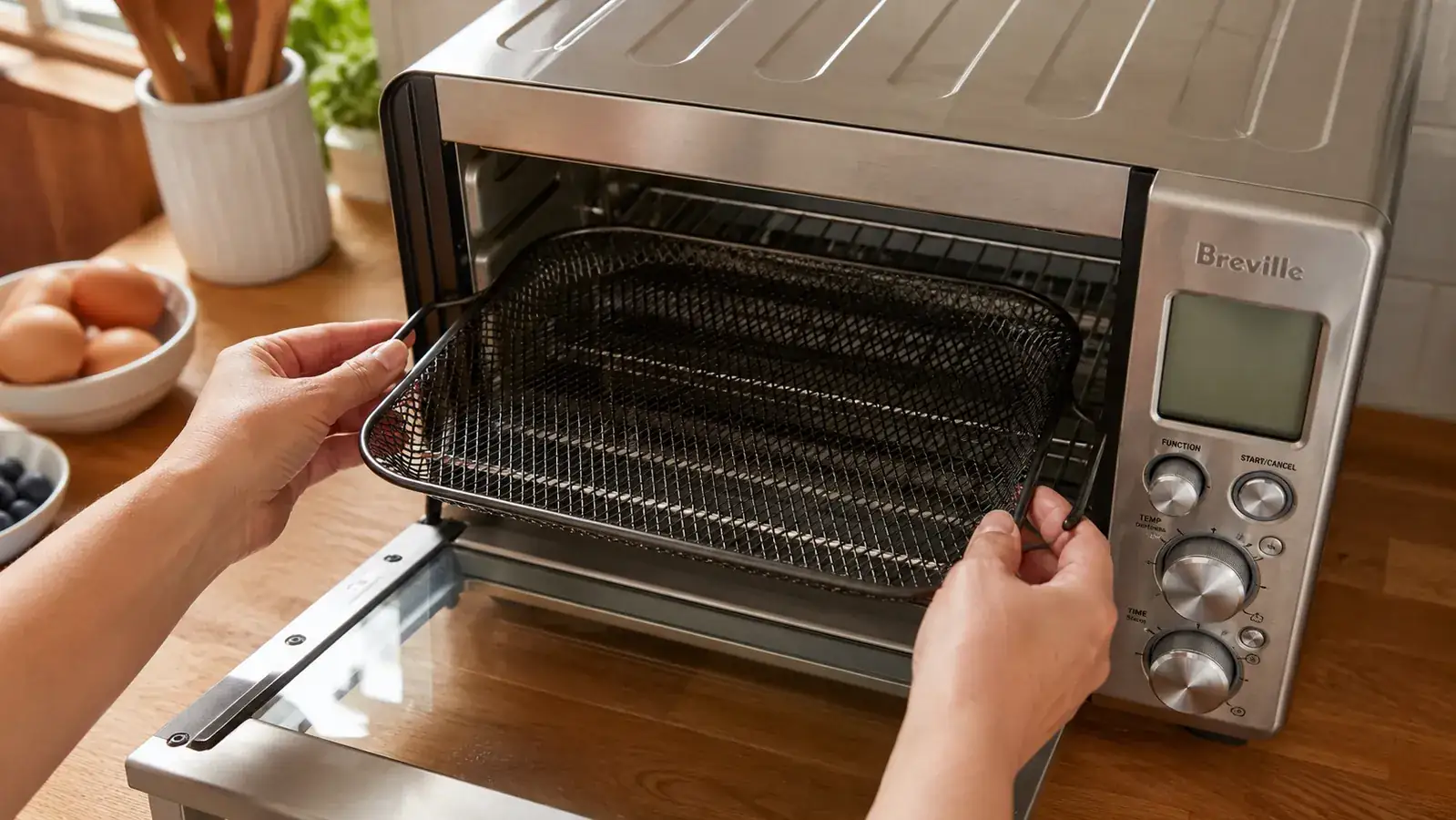 Close-up of a hand sliding the air fry basket into the Breville BOV900 on the second rack position from the top