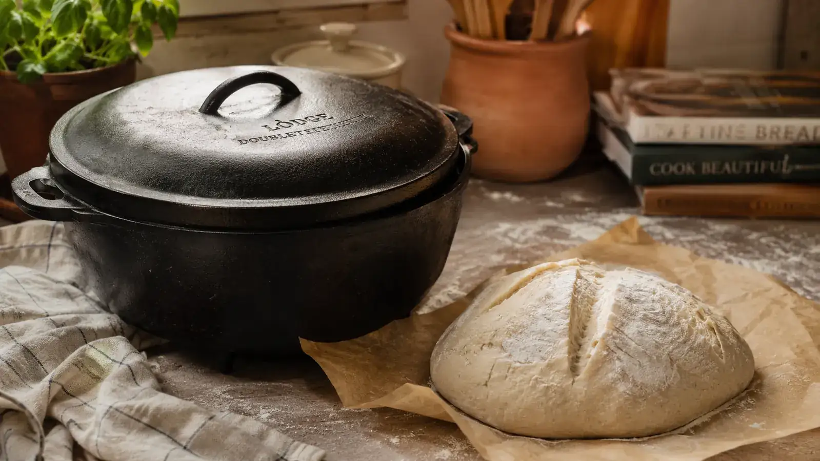 Lodge Cast Iron Double Dutch Oven sitting on a kitchen counter next to a scored sourdough boule ready for baking